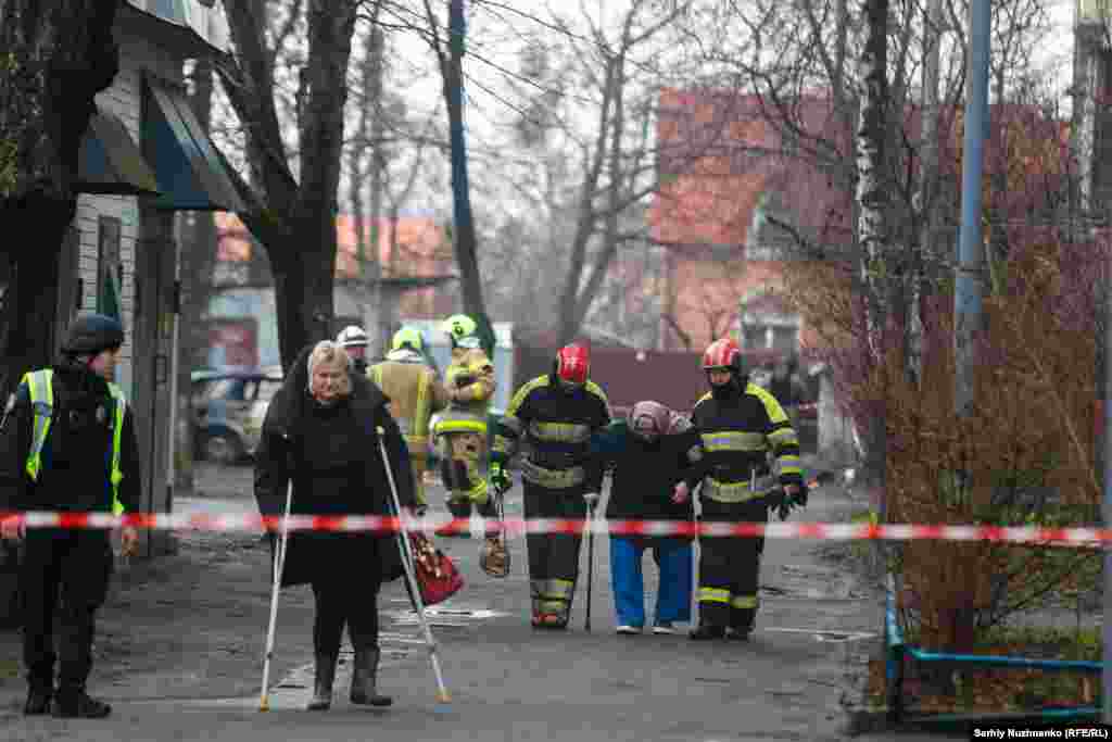 Сотрудники службы экстренного реагирования помогают жителям покинуть свои дома после ракетной атаки