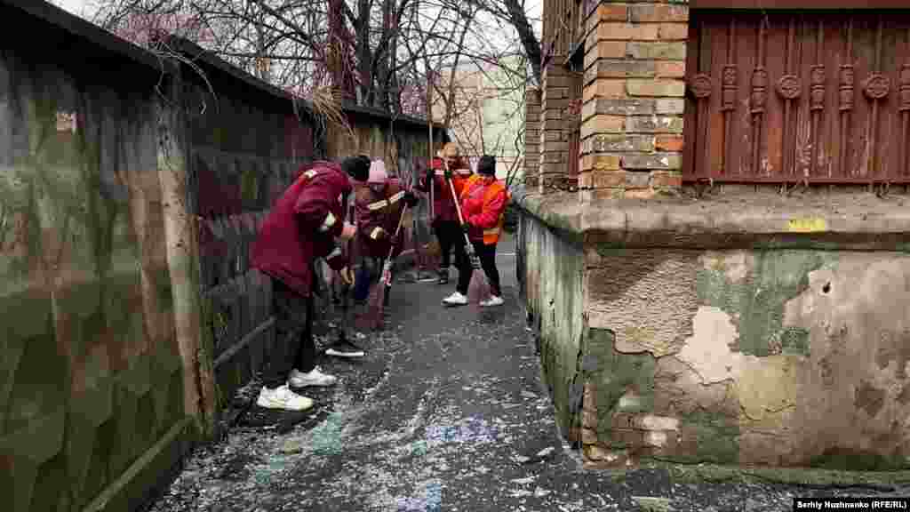 Сотрудники городских служб очищают асфальт от осколков стекла возле здания