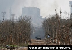 Мариуполь көшесінде жүрген Ресей әскери беренді техникасы. Арғы жағында совет дәуірінде салынған "Азовсталь" металлургия комбинаты тұр. 12 сәуір 2022 жыл.