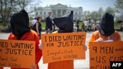 U.S. -- Black hooded human rights activists hold banners demanding the closing of Guantanamo during a protest, part of the Nationwide for Guantanamo Day of Action, outside the White House in Washington DC on 11Apr2013