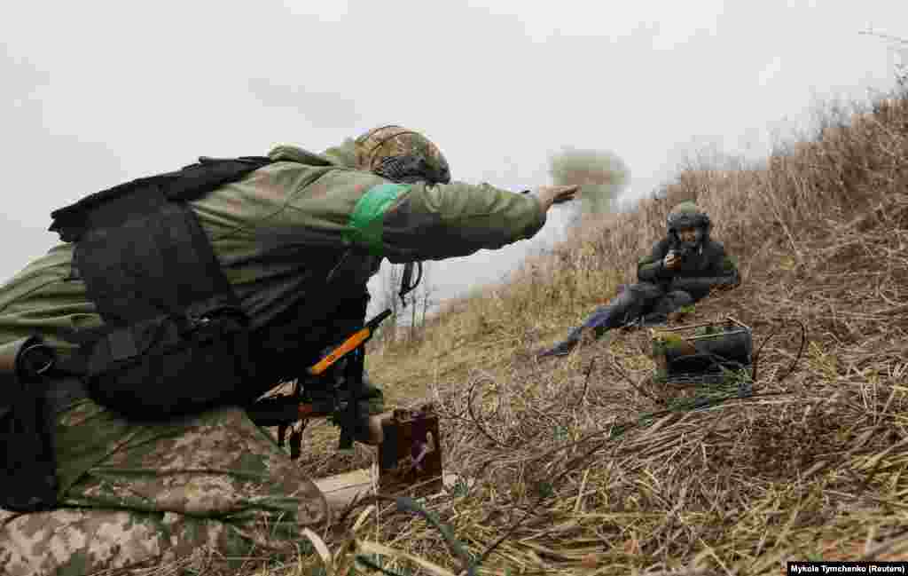 Фотограф снимает момент, когда украинский сапер подрывает неразорвавшиеся боеприпасы, собранные в Мотыжине и его окрестностях. 10 апреля 2022 года