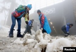 Рабочие убирают снег на лыжной трассе. Сочи, 17 февраля 2014 года.