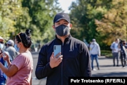 Билік өткізуге келісім берген митингіде бетіне маска тағып, смартфон ұстап жүрген ер адам. Алматы, 13 қыркүйек 2020 жыл.