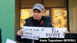 Активист Макс Бокаев проводит пикет в поддержку арестованных активистов Серикжана Мамбеталина и Ермека Нарымбаева перед зданием суда Алматы. 26 октября 2015 года.