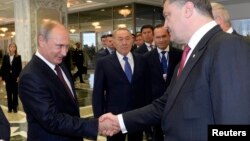 Президент Украины Пётр Порошенко (справа) и президент России Владимир Путин (слева) приветствуют друг друга. Рядом стоит президент Казахстана Нурсултан Назарбаев. Минск, 26 августа 2014 года.