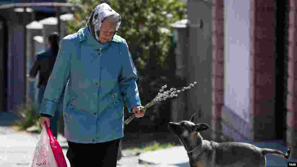 Жінка з гілочками верби на одній із вулиць міста