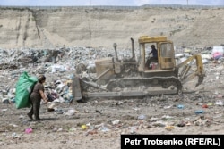 Күресінде жұмыс істеп жүрген трактор және қап арқалап, бөтелке жинап жүрген адам. Алматы облысы, 22 маусым 2021 жыл.